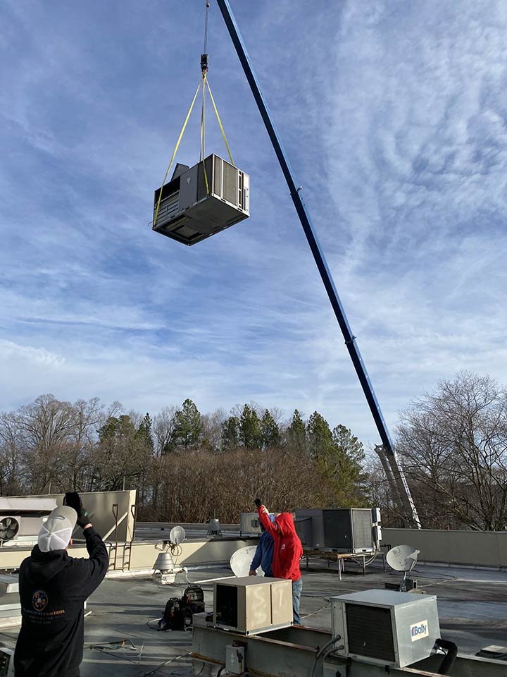 Photo of Temp Control Services technicians lifting an HVAC unit with a crane